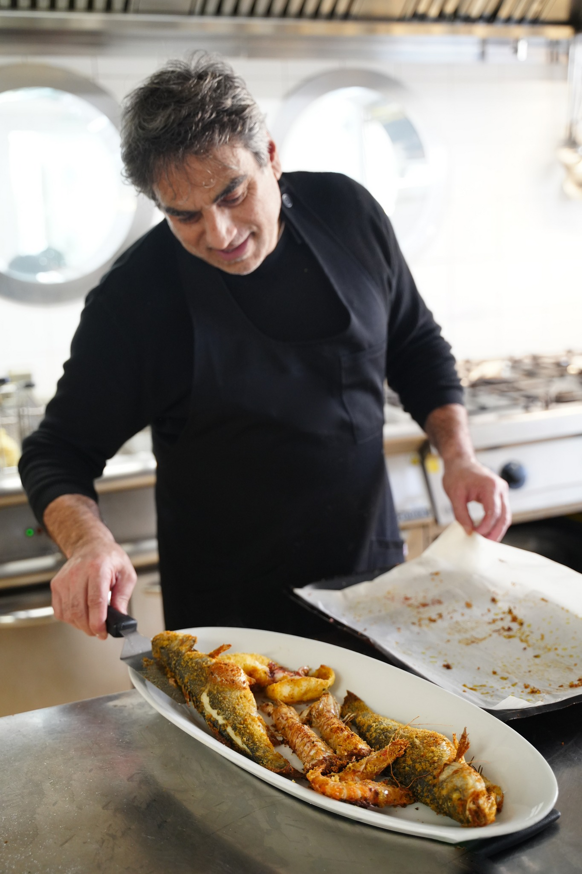 Lo chef impiatta pesce fritto in cucina